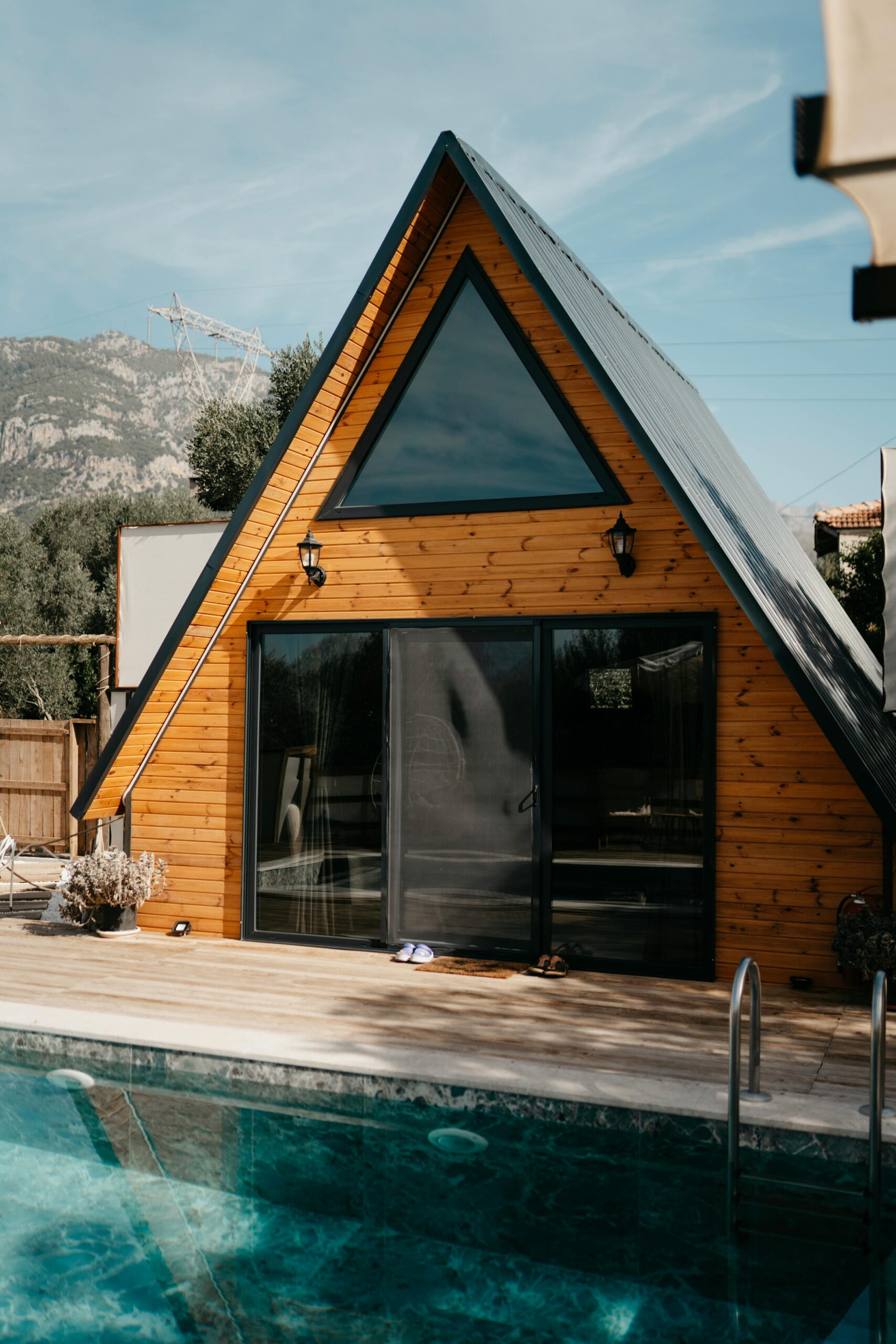 A picturesque A-frame cabin beside a pool under clear skies in Ortaca, Türkiye.